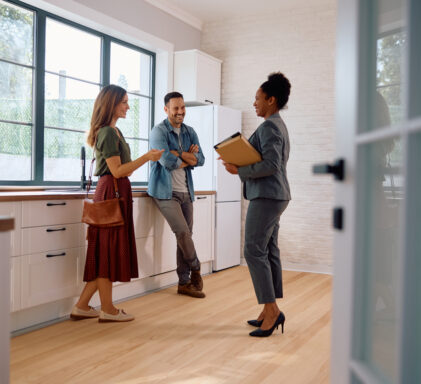 Happy black real estate agent and a couple in the kitchen of a new house.