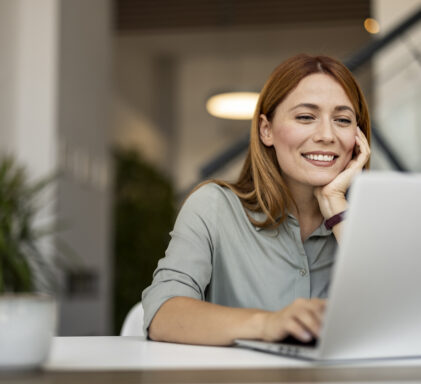 Smiling Woman Working Remotely on Laptop in Modern Workspace